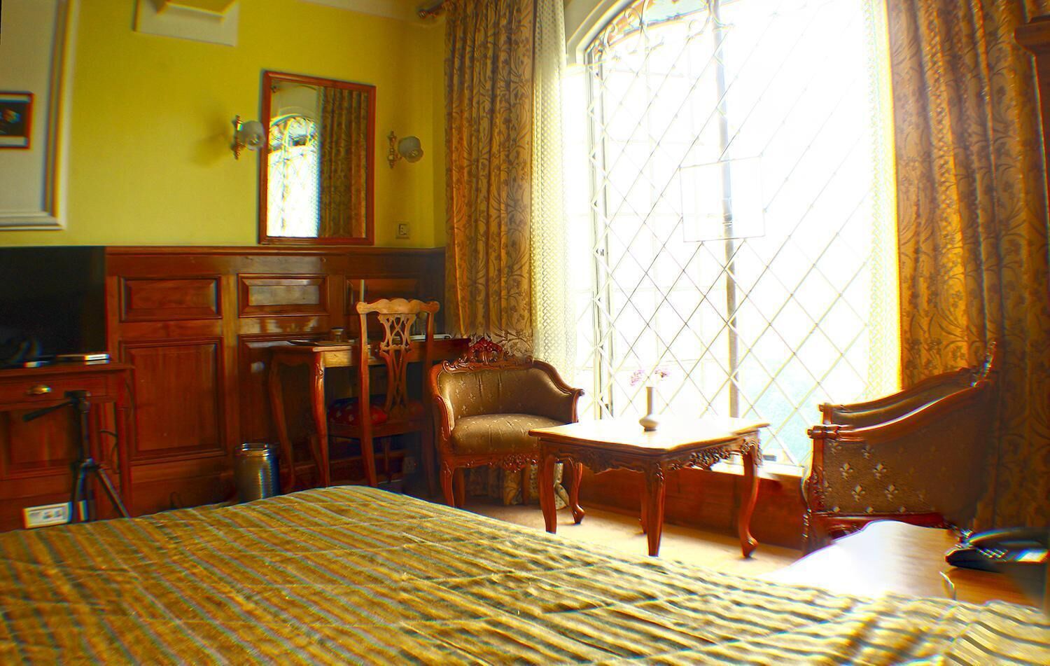 Une chambre d’hôtel avec un grand lit, un bureau, une chaise et une fenêtre avec des rideaux.