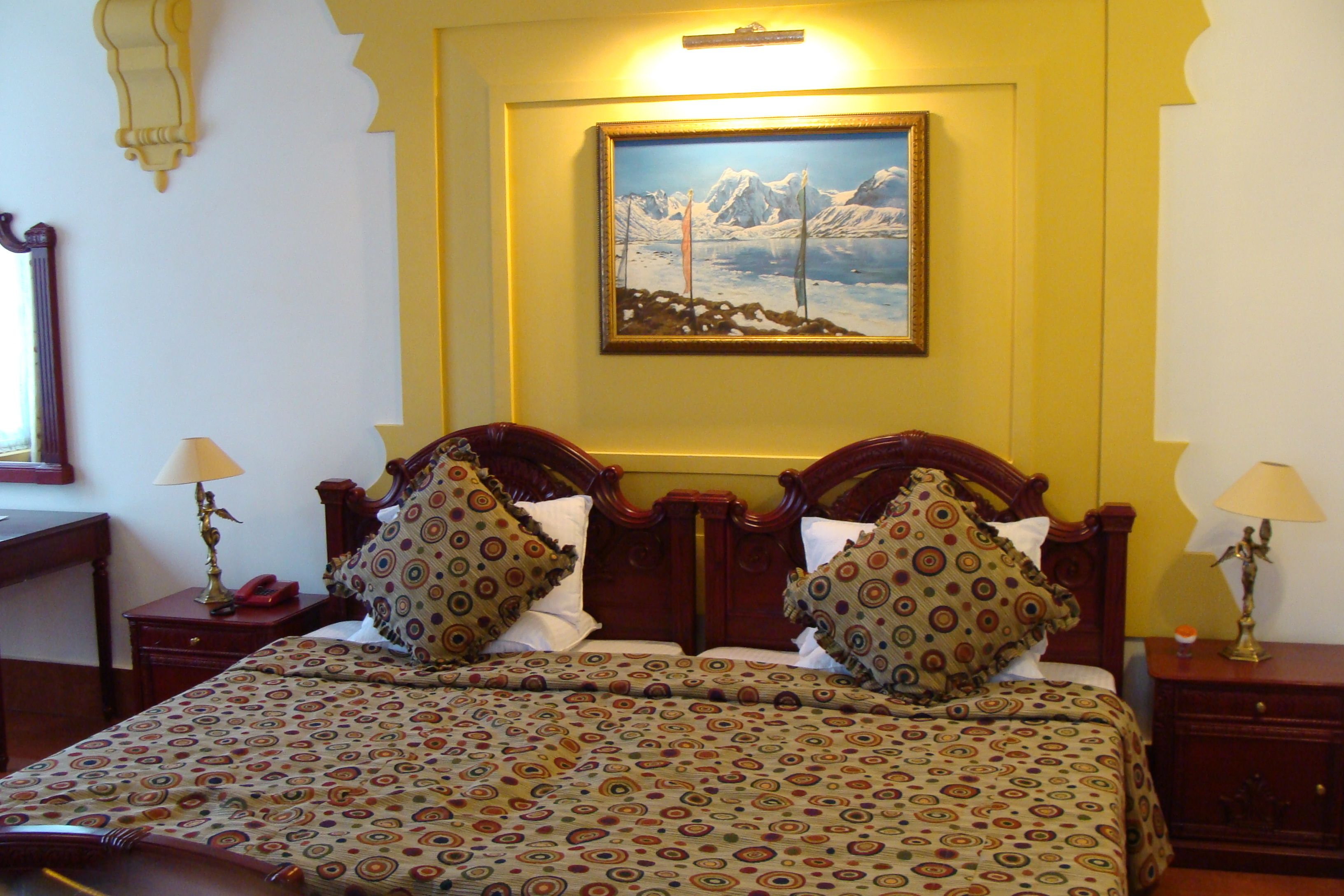 Una habitación de hotel con cama, dos mesitas de noche, un cuadro en la pared y una ventana.