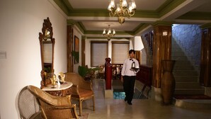 A spacious lobby with a grand chandelier, a staircase, and a dining area with wicker furniture. - Saramsa Resort (Gangtok)