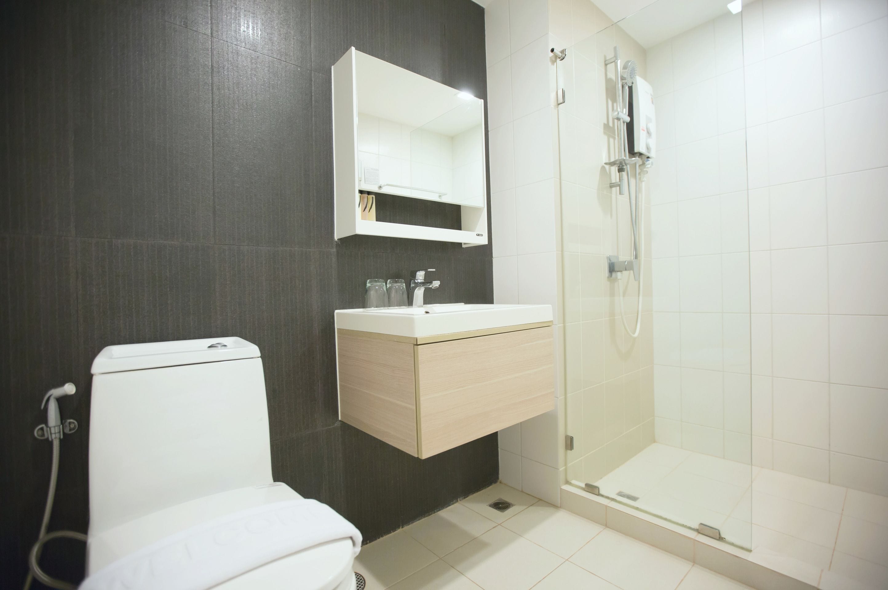 A modern bathroom with a toilet, a sink with a mirror, and a glass-enclosed shower.