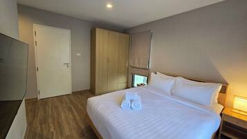 Habitación de hotel con cama, armario, televisor y mesita de noche.