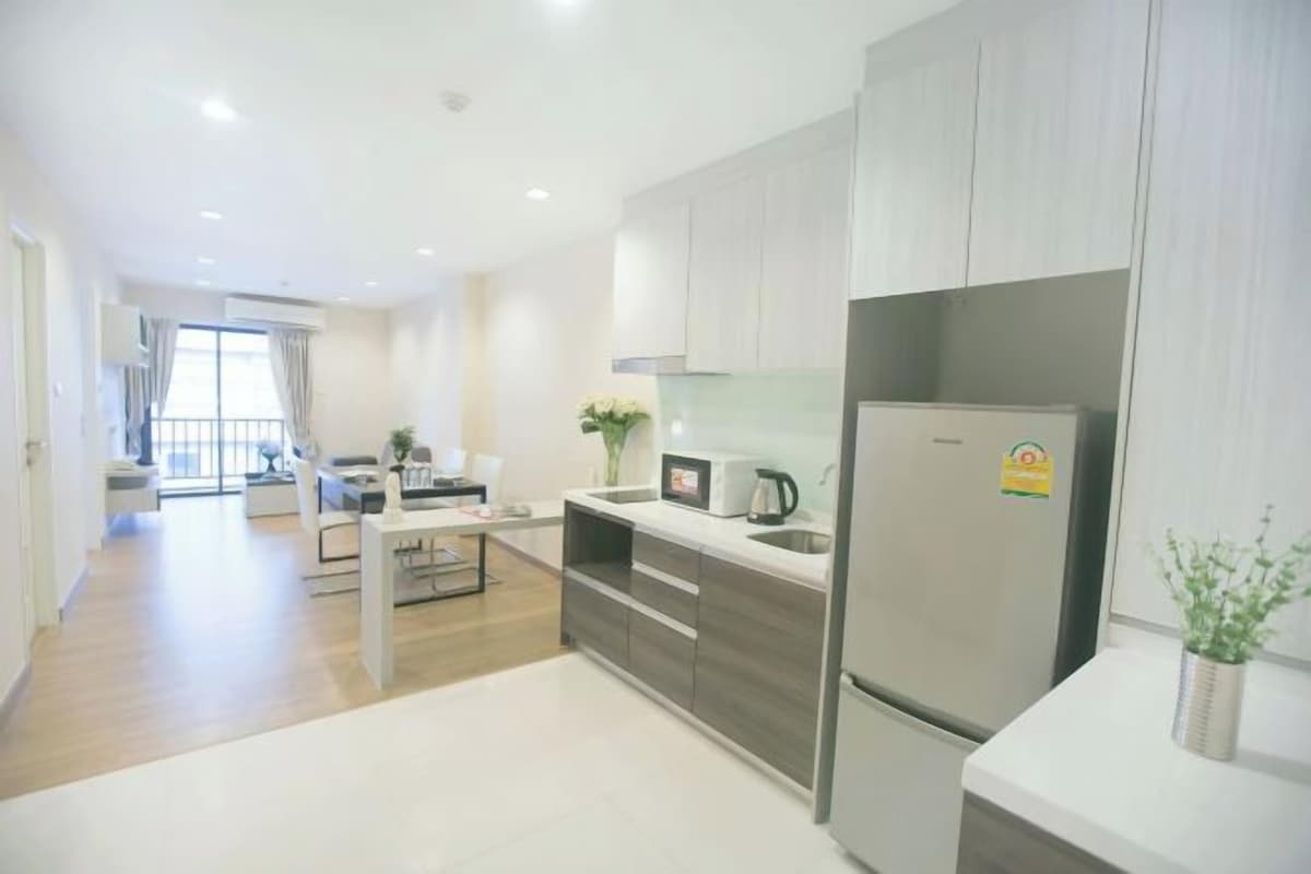 A modern kitchen with a built-in refrigerator, a coffee maker, and a dining area with a table and chairs.