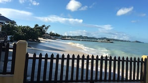 A beach with a wooden fence, clear blue sky, and distant mountains. - Antigua Seaview (St. John's)