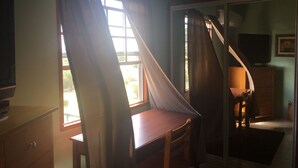 A room with a desk, chair, and a sliding door leading to another room. - Antigua Seaview (St. John's)