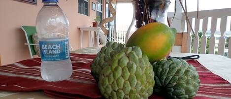 A table with a water bottle, a mango, and two artichokes on a red tablecloth.