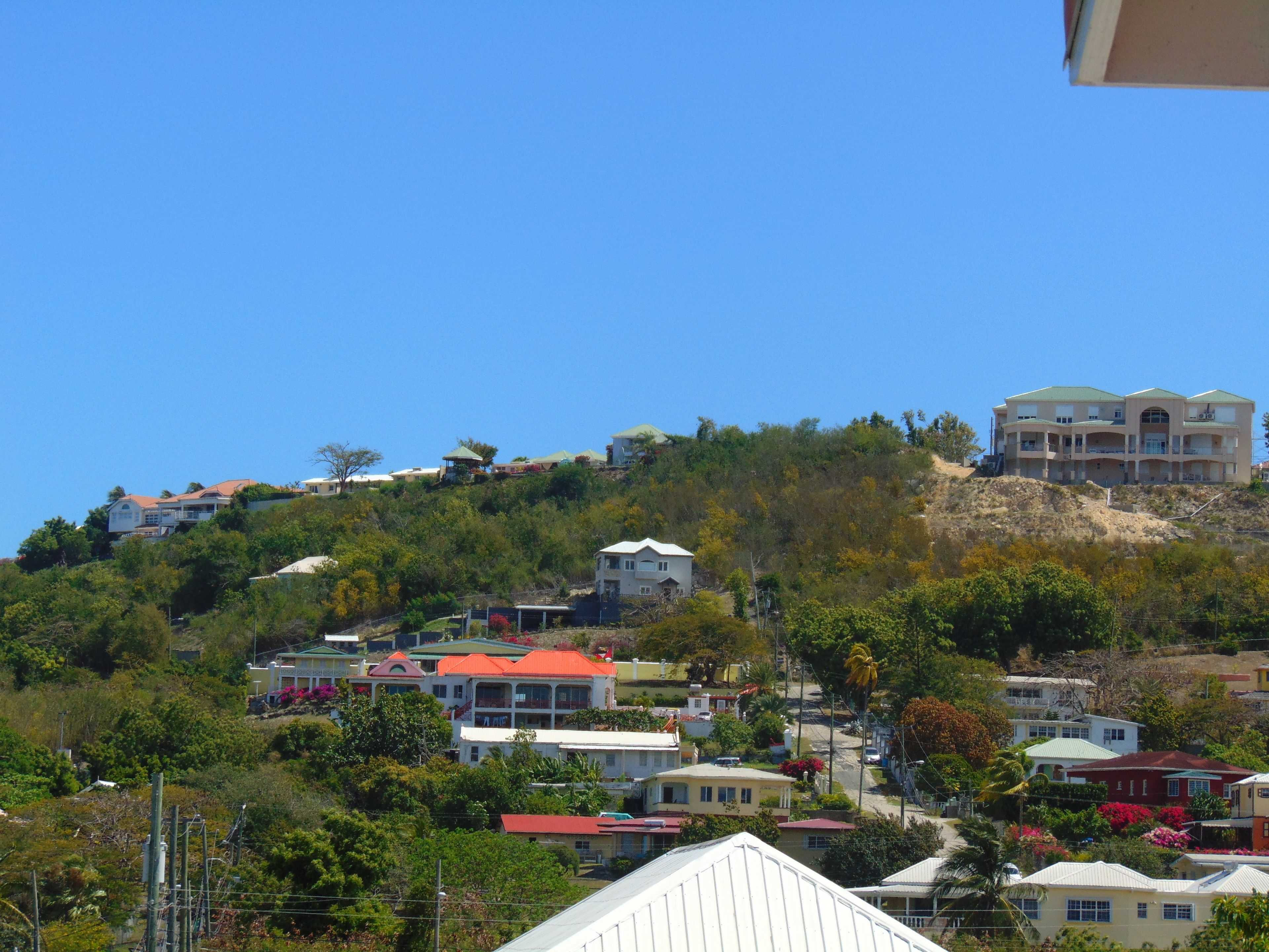 Un quartier résidentiel situé sur une colline, avec des maisons et un grand immeuble doté de nombreux balcons.