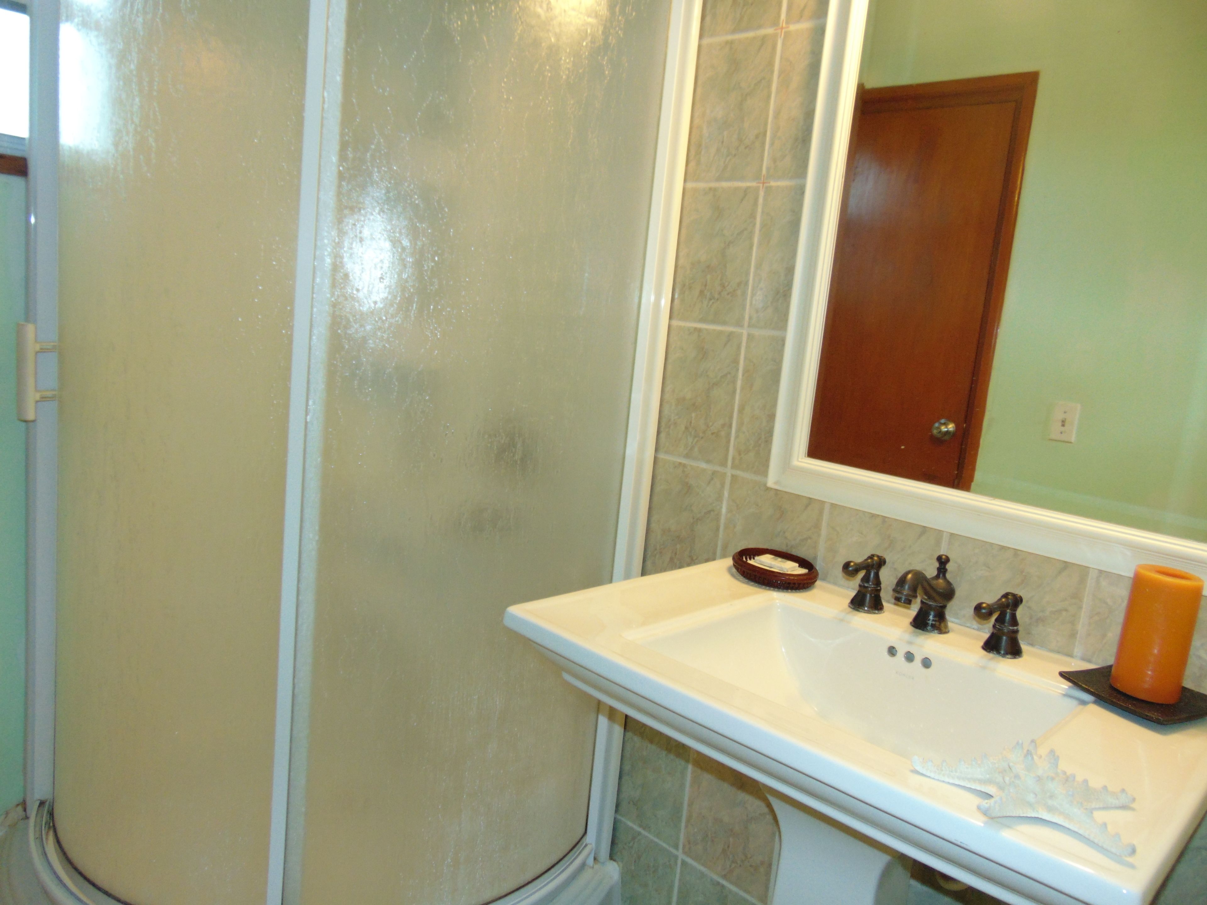 Une salle de bain avec un lavabo blanc, un miroir et une douche.