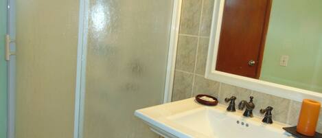Une salle de bain avec un lavabo blanc, un miroir et une douche.