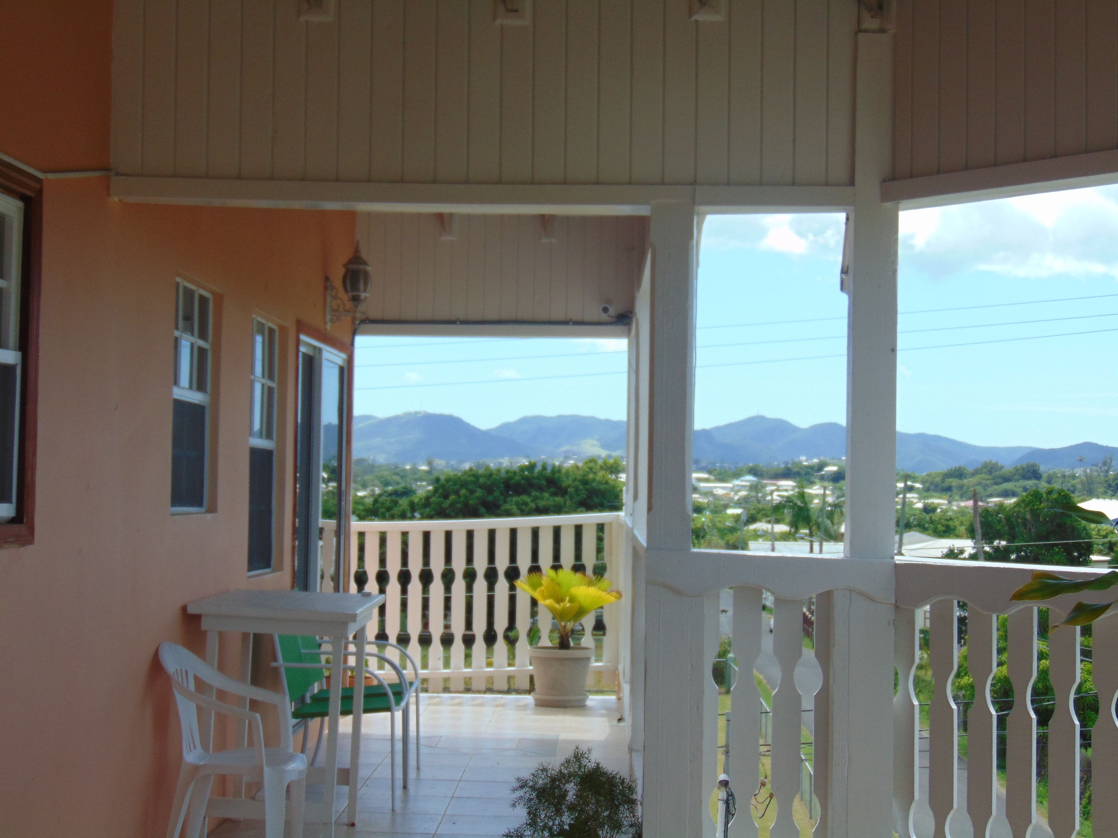 Un balcon avec vue sur les montagnes, une table avec des chaises et une plante en pot.