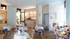 A dining area with multiple tables and chairs, a kitchen in the background, and a buffet table with various food items. - Subretia Residenze di Campagna (Montefalco)