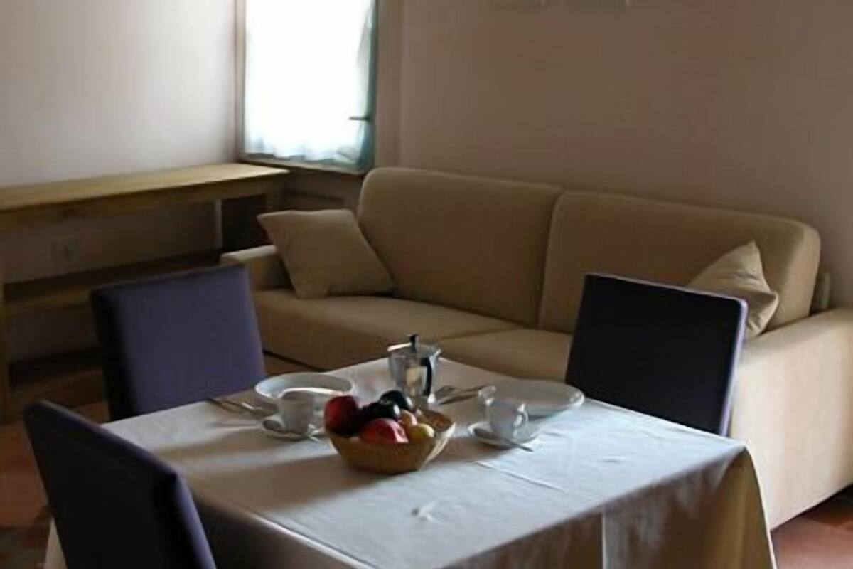 Un coin repas avec une table dressée pour deux personnes, un canapé et une fenêtre avec des rideaux.