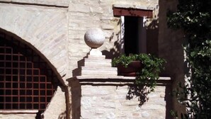 A stone building with a wooden staircase leading to a door with a metal grille. - Subretia Residenze di Campagna (Montefalco)