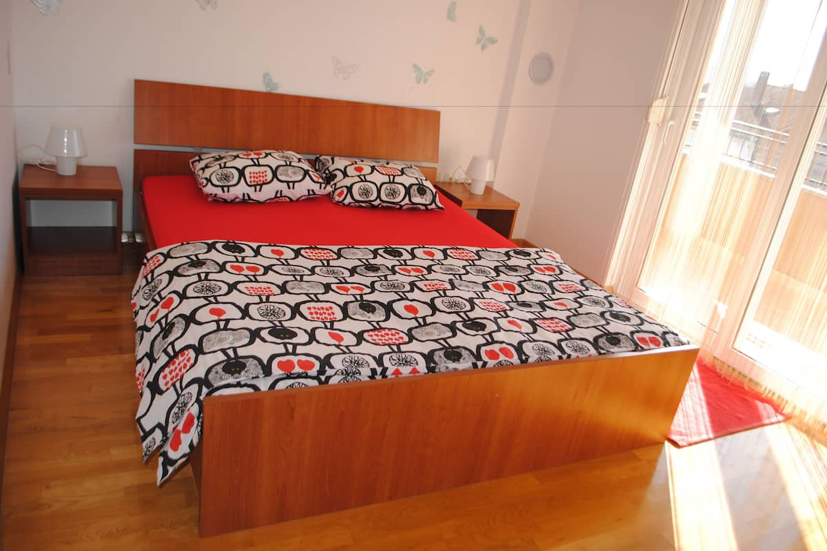 A bedroom with a wooden bed, red bedding, and butterfly wall decals.