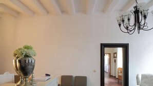 A room with a chandelier, a large vase with flowers, a white sofa, and two chairs. - Das Dycker Weinhaus (Juechen)