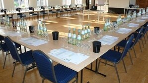 A conference room with long tables, chairs, and glassware. - Das Dycker Weinhaus (Juechen)