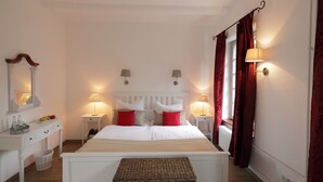 A neatly arranged bedroom with a large bed, two bedside tables with lamps, a dresser, and a small wicker ottoman. - Das Dycker Weinhaus (Juechen)