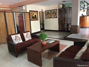 A hotel lobby with a sofa set, a coffee table, and a potted plant. - Soledad Suites (Tagbilaran)