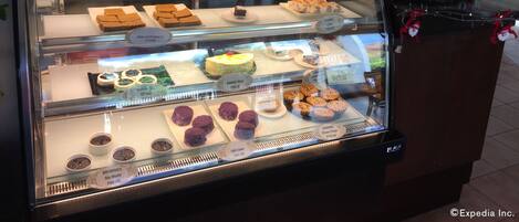 A bakery display case with various baked goods like bread pudding, mango slices, and brownies.