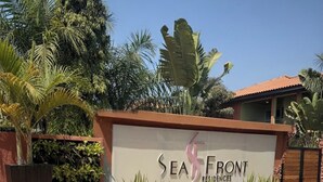 Letrero de SeaFront Residences con entrada ajardinada que presenta diversas plantas y un cielo despejado.