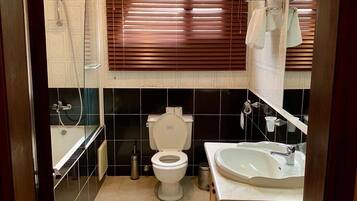 Un baño con inodoro, lavamanos, ducha y toallero.