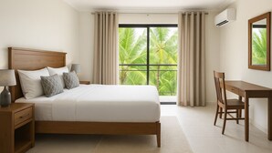 Habitación de hotel con una cama grande, un escritorio y vistas a palmeras a través de la ventana.
