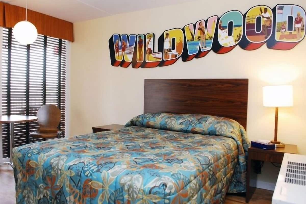 A hotel room with a bed, a nightstand, a lamp, and a wall decoration spelling "WILLOWOOD".