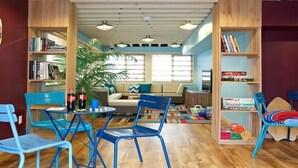 Una sala de estar acogedora con sillones azules, un sofá y una estantería llena de libros.