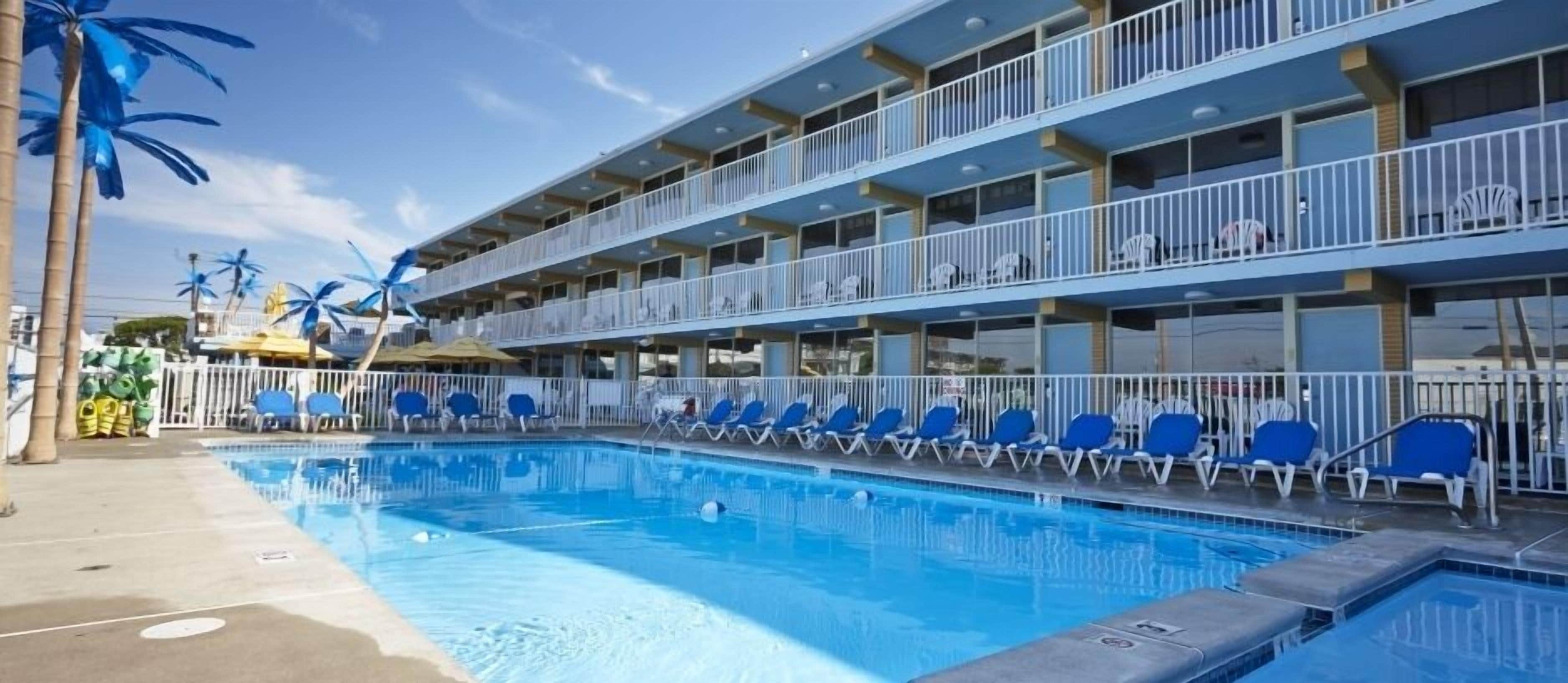 A hotel with a swimming pool, multiple balconies, and outdoor seating.