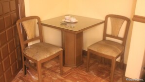 A small dining area with a glass-top table and two wooden chairs with cushioned seats. - Halina Drive Inn Hotel - Pasay (Pasay)