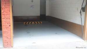 A parking garage with a brick wall and a white floor. - Halina Drive Inn Hotel - Pasay (Pasay)