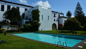 A modern building with a swimming pool, surrounded by well-maintained lawns and trees. - Convento de São Francisco (Vila Franca do Campo)