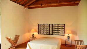 A bedroom with a bed, two chairs, a decorative wall piece, and two lamps. - Convento de São Francisco (Vila Franca do Campo)