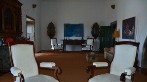 A room with four wooden chairs, a blue painting on the wall, and a green door. - Convento de São Francisco (Vila Franca do Campo)