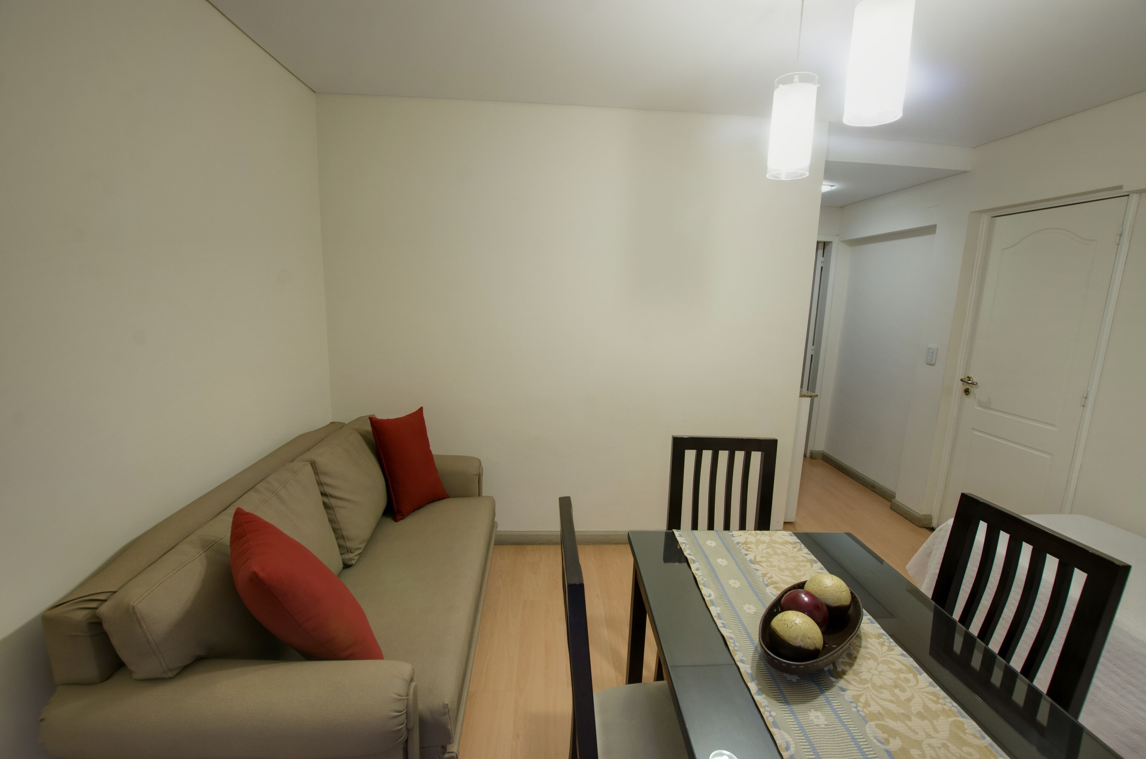 A dining area with a table, chairs, and a sofa with red cushions.