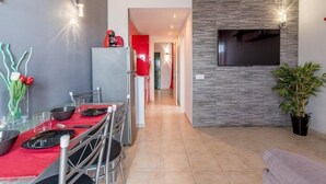 Une cuisine moderne avec un coin repas, un téléviseur fixé au mur et une plante en pot.