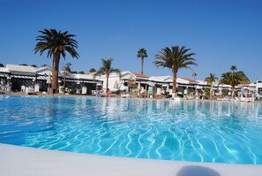 Ein Swimmingpool mit Liegestühlen und Palmen.