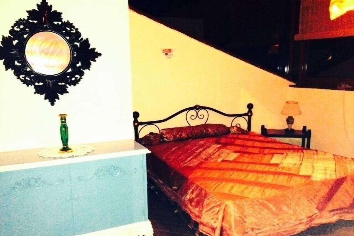 A bedroom with a bed, a dresser, a mirror, and a lamp.
