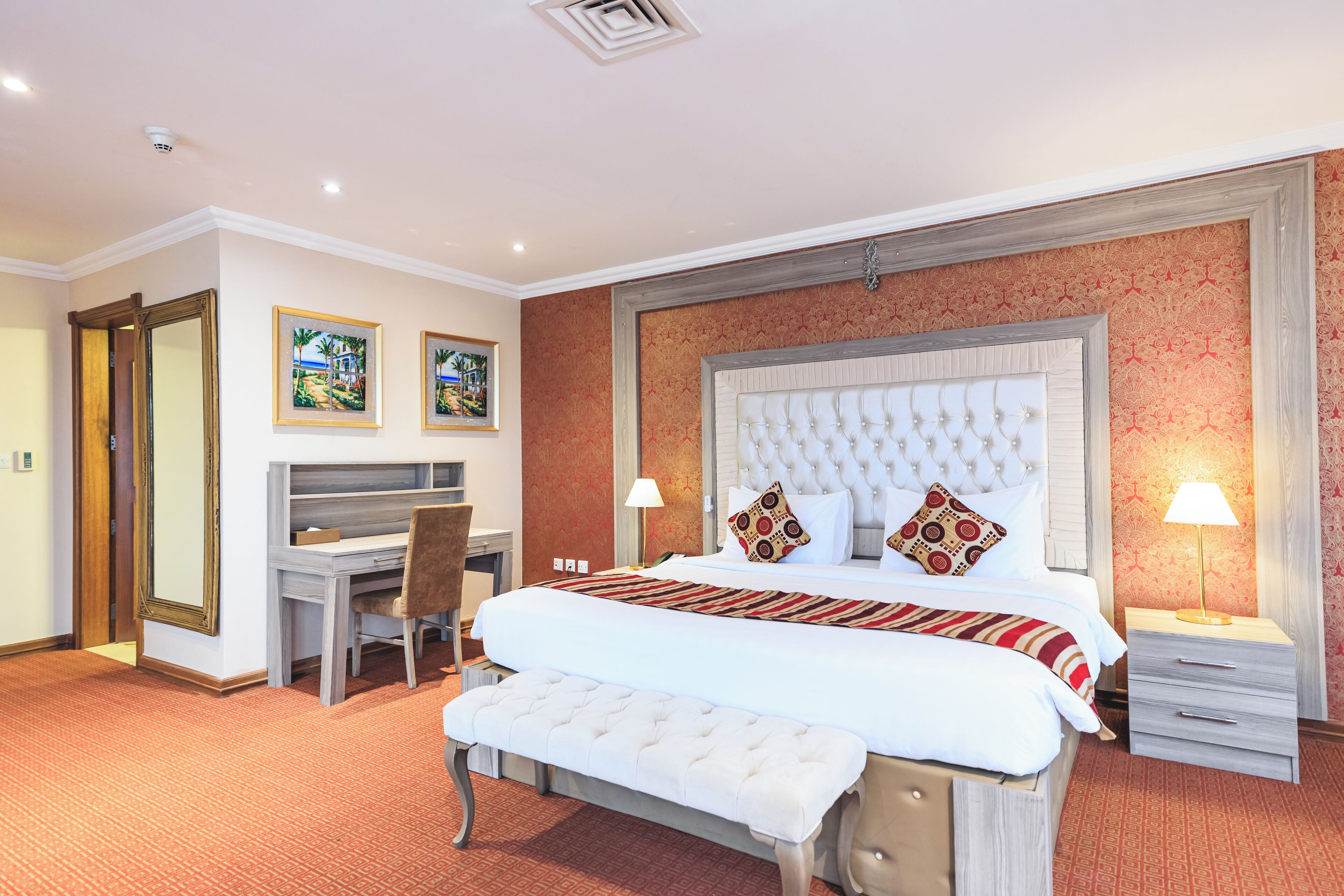 Ein Hotelzimmer mit einem großen Bett, einem Schreibtisch, einem Sessel und einer Bank.