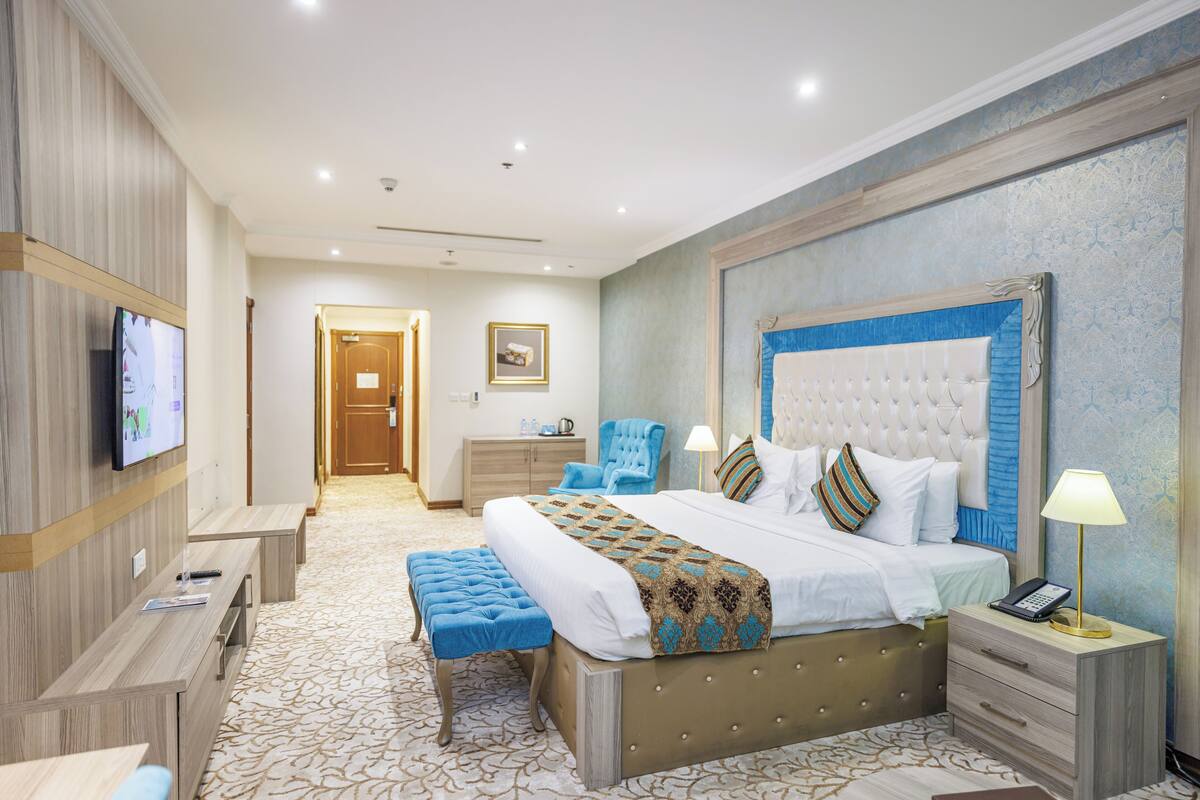 A hotel room with a large bed, a TV, a desk, and a chair.