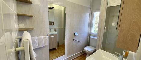 Un baño moderno con un espejo grande, un lavabo y un inodoro. Hay un perchero con una toalla blanca.