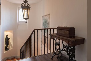 A staircase with a wooden handrail and a metal balustrade, a decorative lantern, and a framed botanical print on the wall.