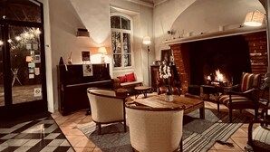 A cozy living room with a fireplace, a chandelier, and a checkered floor. - Logis hôtel la Bellaudière (Grasse)