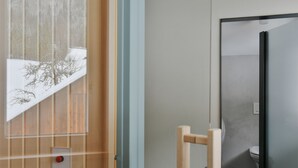 Ein modernes Badezimmer mit Toilette, Duschbereich und einer Glastür, die auf eine verschneite Winterlandschaft führt.