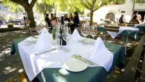 Ein Tisch für eine Mahlzeit im Freien mit weißer Tischdecke, grünen Servietten und klaren Gläsern.
