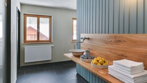 Ein Badezimmer mit einem Holzinlay, einem Waschbecken, einem Spiegel und einem Fenster mit Blick auf eine Holzhütte.