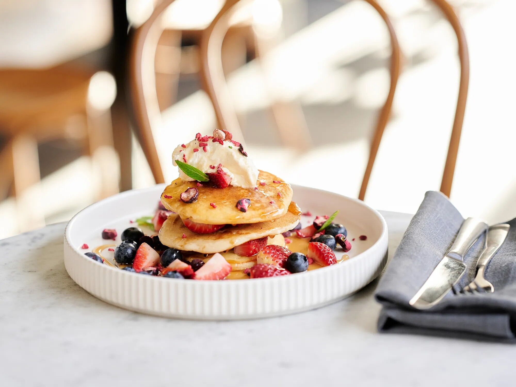 Um prato de panquecas com frutas vermelhas e chantilly.