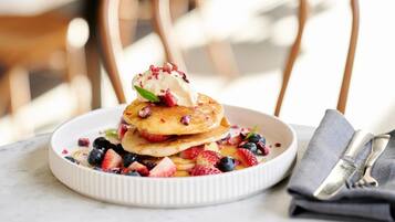 Um prato de panquecas com frutas vermelhas e chantilly.