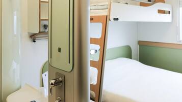 Ein Hotelzimmer mit Bett, Nachttisch, Spiegel und Waschbecken.
