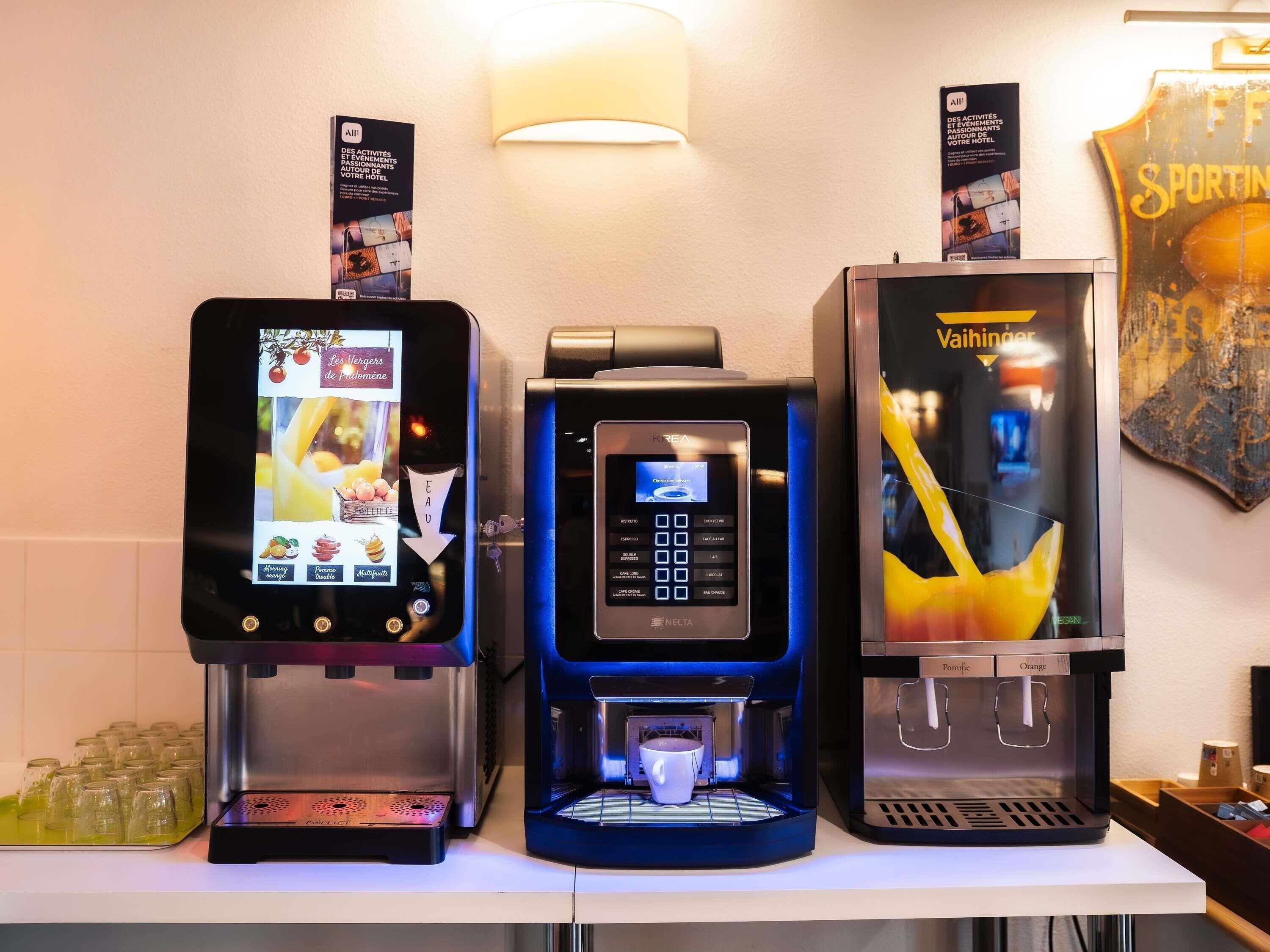 Tres máquinas de café con pantallas digitales, una lámpara en la pared y un cartel.