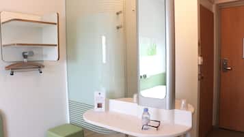 A bathroom with a white sink, a mirror, and a shower area.